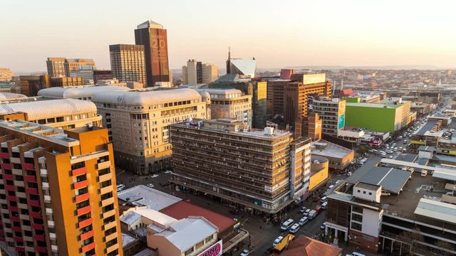 Loop of Medium timelapse at sunset/nightfall showing the view across New Town. Jeppes town and the city centre of Johannesburg during peak traffic with the hustle and bustle of people in the streets, buildings and taxis, South Africa