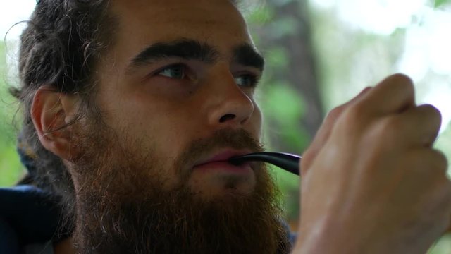 Close up of attractive man with beard smoking on the beach. Outside. Portrait