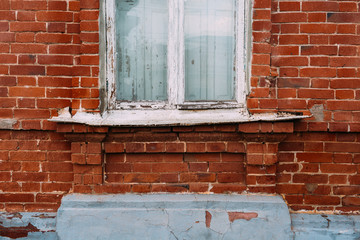 Old destroyed brick wall. White wooden window with iron window sill
