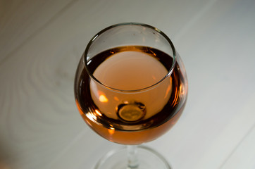 Glass of rose wine on white wooden table in the dark