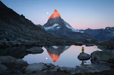 Photo sur Plexiglas Cervin A girl on a rock in the Riffelsee watching the first sunlight shining on the Matterhorn.