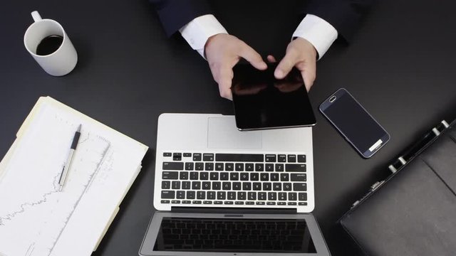Loop of Top view of businessmans desk with laptop, cellphone, tablet, coffee and suitcase