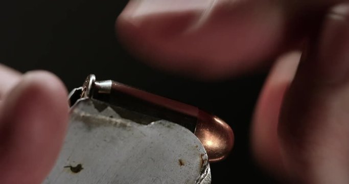 Loop of Person loads bullets into magazine, close up