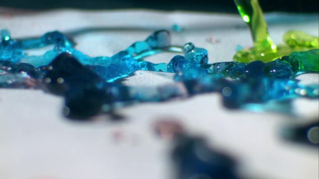 Loop of Multicolored gelatin substance moves on the ground, close up