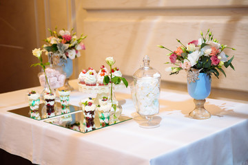 Candy bar, a table with sweets and desserts on the table. Buffet with delicious cupcakes, cake pops, biscuits, flowers.