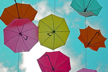 colorful umbrellas on a background of clouds. View from the bottom to the sky