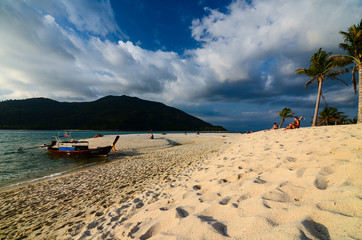 Beautiful beach with a boat and palm trees in koh Lipe, Thailand