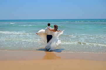 Fototapeta na wymiar the groom in a suit carries on his hands the bride in a wedding dress in the waters of the Indian Ocean. Wedding and honeymoon in the tropics on the island of Sri Lanka