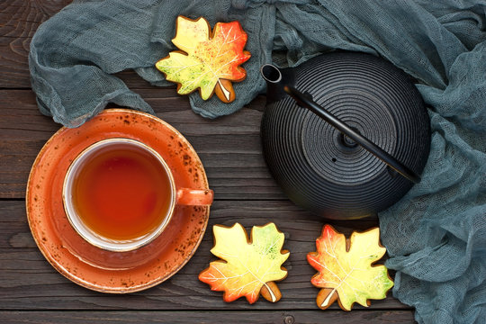 Mug of hot tea, cookies   form autumn leaves, on wooden table