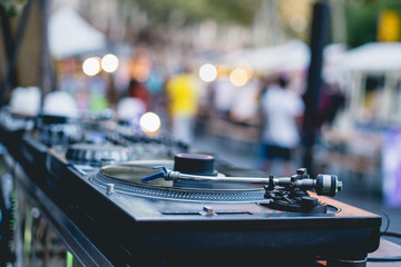 DJ mixing vinyl records console turntable. Shallow depth of field, bokeh daily lights