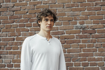 Close up of young attractive man standing on red brick background.