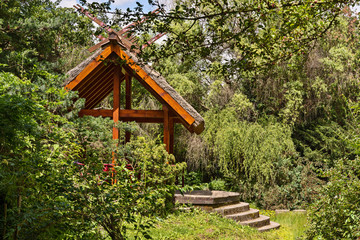 Shelter, wooden gazebo in the park and green grass