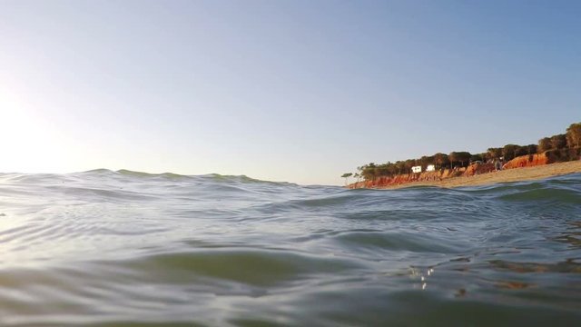 Shooting from sea, sunset and waves cover camera. Portugal Algarve.