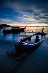 Sunset on a beach with silouhette of boats in Thailand