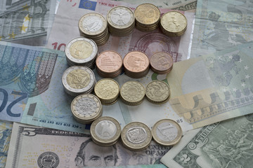 Towers of euro coins in the form of a euro sign. Banknote background. Euro and US dollars currency. Selective focus.
