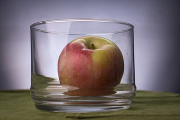 Fresh apple in a glass jar on a green cloth