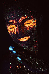 Portrait of a girl painted in fluorescent powder. Halloween concept.