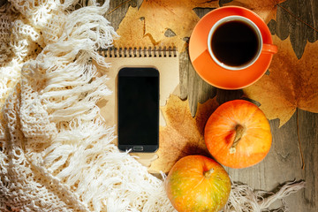 Autumn background with yellow maple leaves, black phone and black coffee. Layout for seasonal offers and holiday cards, top view. Golden October. Selective focus.