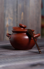 Clay pot with a spoon on a wooden table. The concept of cooking tasty and healthy food.