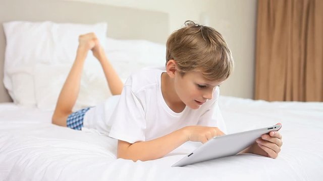 Loop of Smiling boy touching a tablet computer