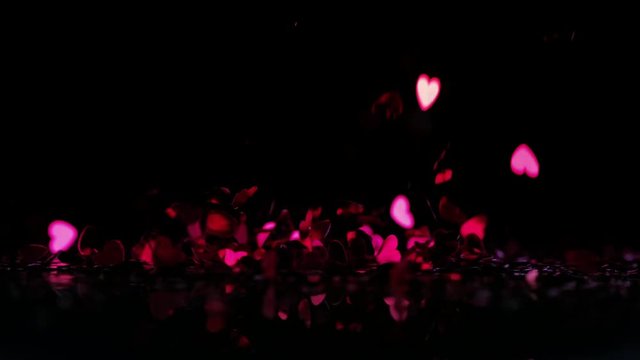 Loop of Pink heart confetti falling down on black background