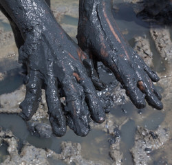 Hands smeared with black healing mud