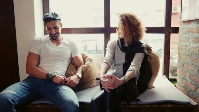 Shy man talking to woman in a cafe by the window