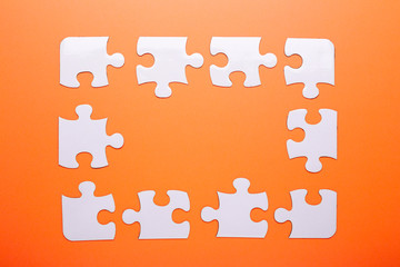 White puzzle on orange background. Missing piece. Top view