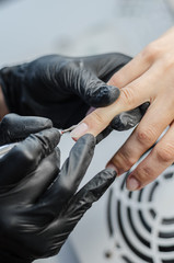 The manicure master makes a hardware manicure with a milling cutter.