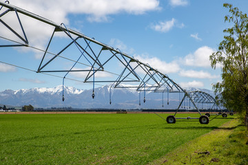A central pivot irrigator set up on a rural farm in a large field ready to irrigate crops in...