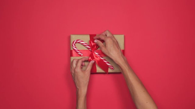 Hands tying red bow on Christmas present box