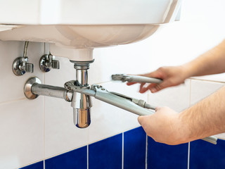 plumber adjusts pipe-wrenches to install a siphon