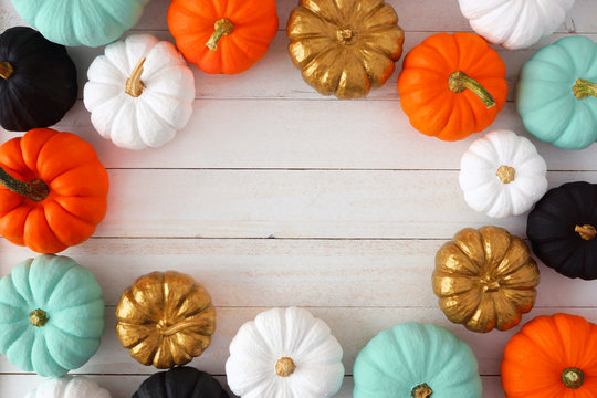 Autumn frame of various colorful pumpkins on a white wood background. Top view with copy space.