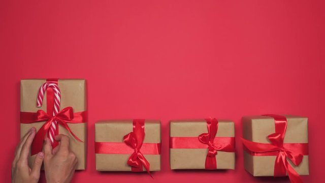 Woman hands putting group of gift boxes over red flat lay
