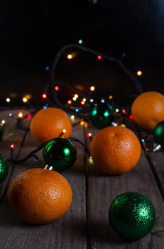 Oranges and green balls on a wooden table, vertical frame.