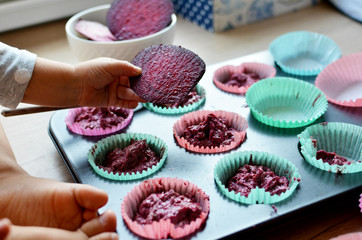 Little hand of girl with beetroot baking muffins