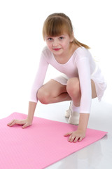 A little girl does gymnastic exercises.