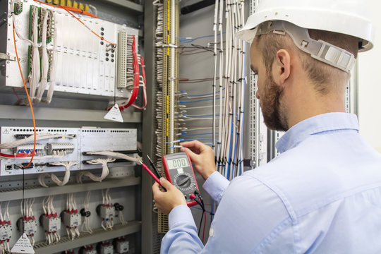 electrician technician in fuse box. Maintenance engineer in control panel. Worker is testing automation equipment. Engineering in electrical station. Electric man with multimeter in hands. Service.