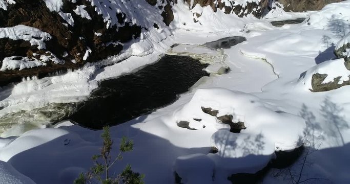 Lapland rapids, C4K aerial rising drone view of a man taking pictures of kiutakongas rapid, in Oulanka national park, on a sunny, winter day, in Kuusamo, Pohjois-Pohjanmaa, Finland