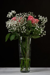A bouquet of flowers in a glass vase on a black background.