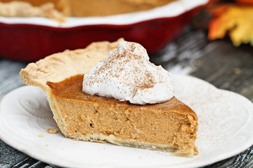 Slice of homemade pumpkin pie over a rustic wooden background. Extreme shallow depth of field with selective focus.