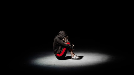 Depressed teenager girl sit on the floor hugging her knees