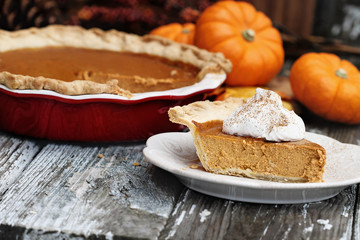 Slice of homemade pumpkin pie over a rustic wooden background. Extreme shallow depth of field with selective focus with blurred background.
