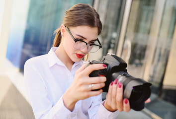 beautiful young girl in white shirt holding in hands the camera presses the shutter button and looks into the viewfinder. Photography, photographer, paparazzi