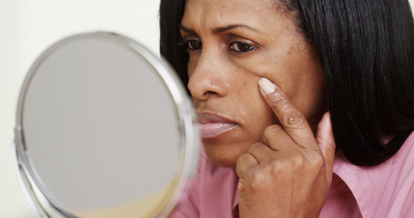 Closeup of black middle aged woman looking into mirror