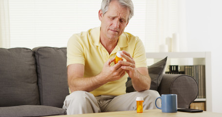 Portrait of worried middle-aged man reading prescription bottle