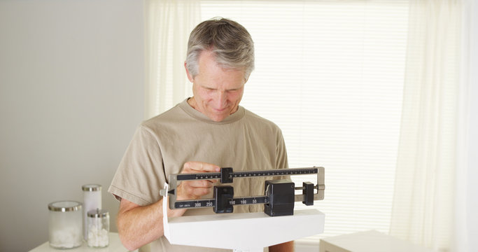 Healthy mid-aged caucasian man weighing himself on scale