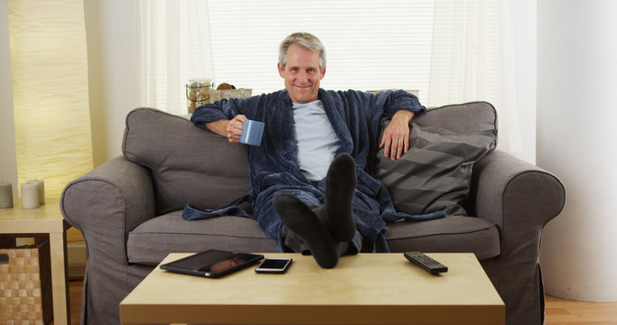 Cheerful Middle-aged Man Relaxed On Couch With Feet On Table