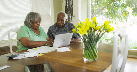 Retired black couple paying bills on the computer