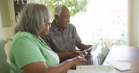 Eldery black man looking at bills with wife